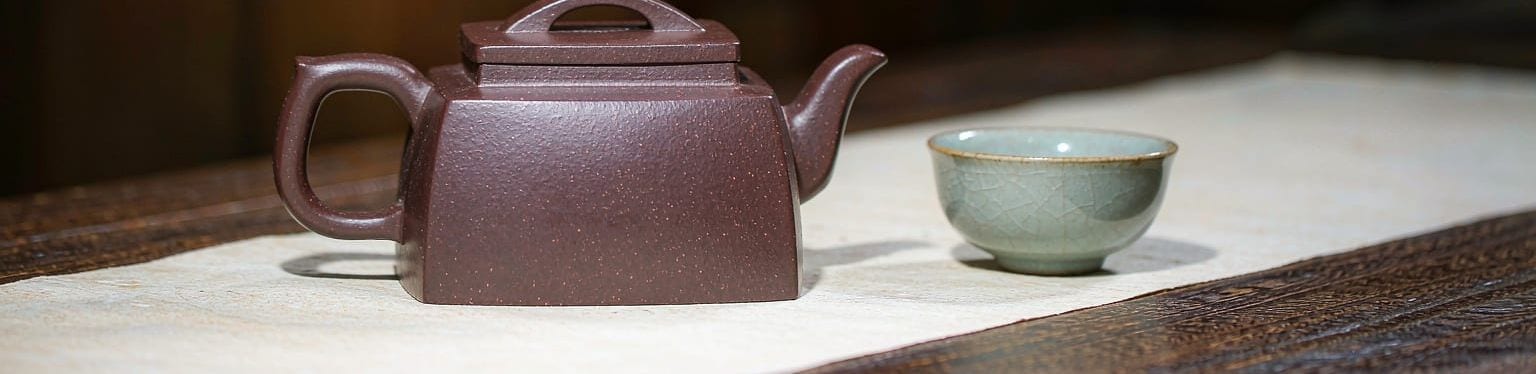 宜兴紫砂石瓢壶与青瓷茶杯，置于宣纸与木质茶席之上